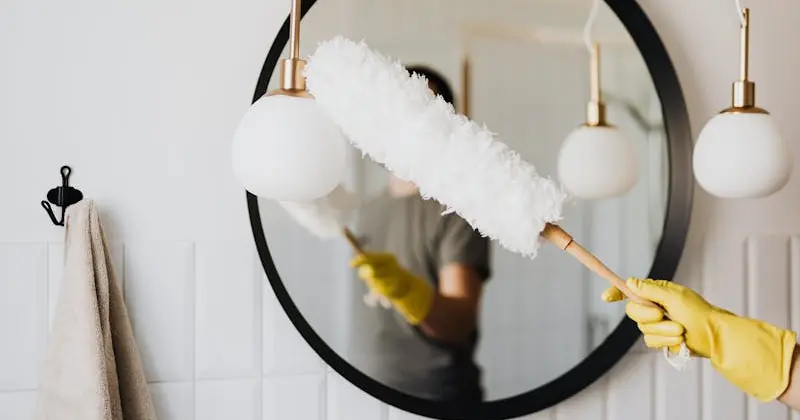 Person cleaning bathroom tile and grout with spray bottle and brush